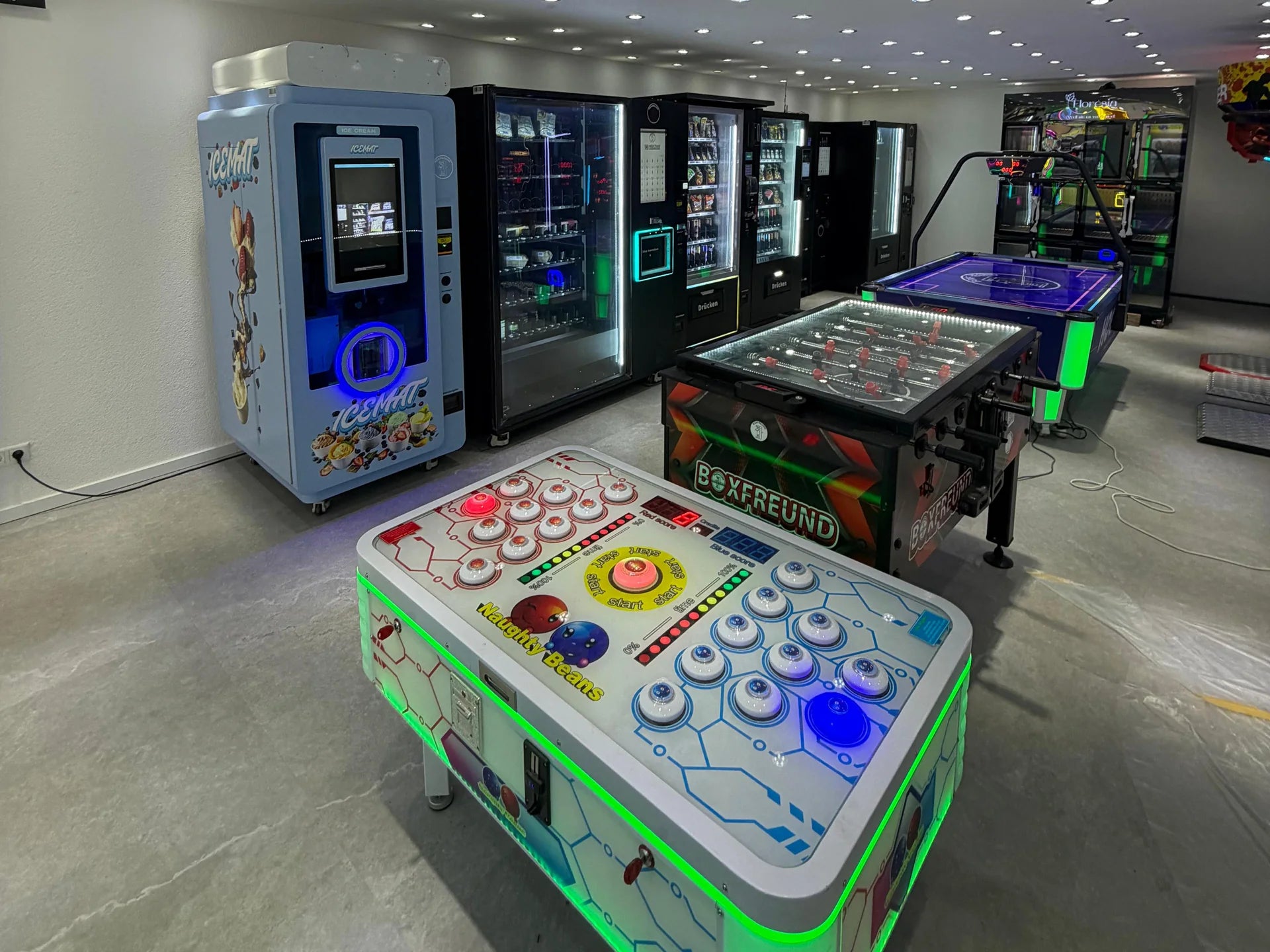 Der Boxfreund-Showroom in Langenfeld: Warenautomaten an der Wand, davor Kicker, Airhockey und Spieltisch